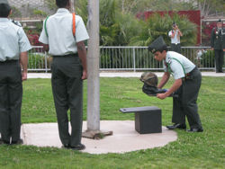 Miguel JROTC Cadet Master Sergeant Guillermo Martinez places an American Flag, a helmet, and a pair of boots at the base of the flag pole.